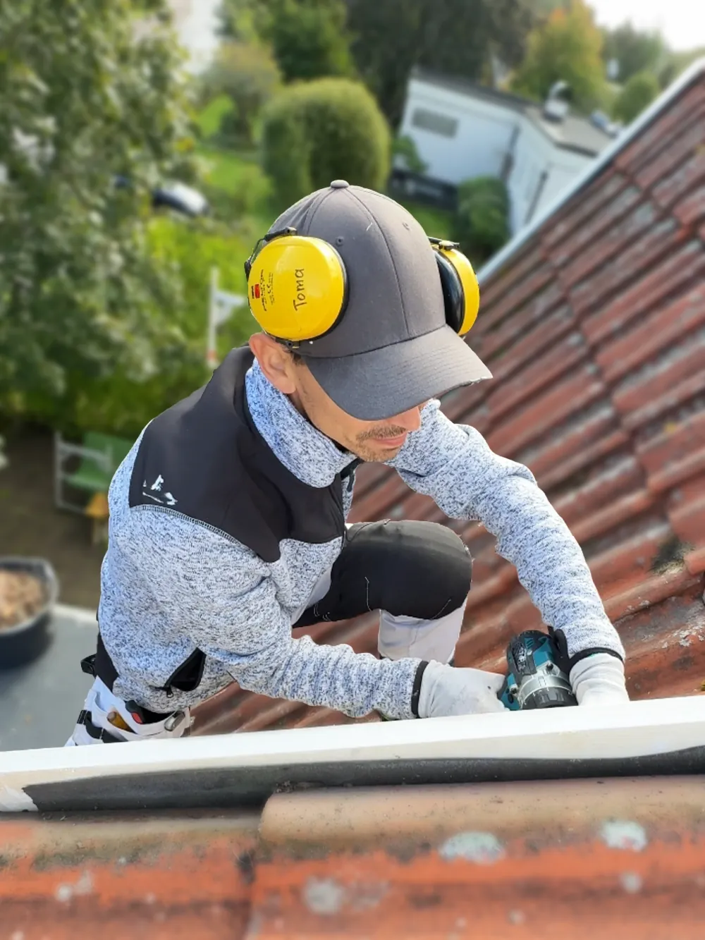 Snickare hos SAVL Solutions på tegeltak monterar vindskiva med skruvdragare och hörselkåpor.