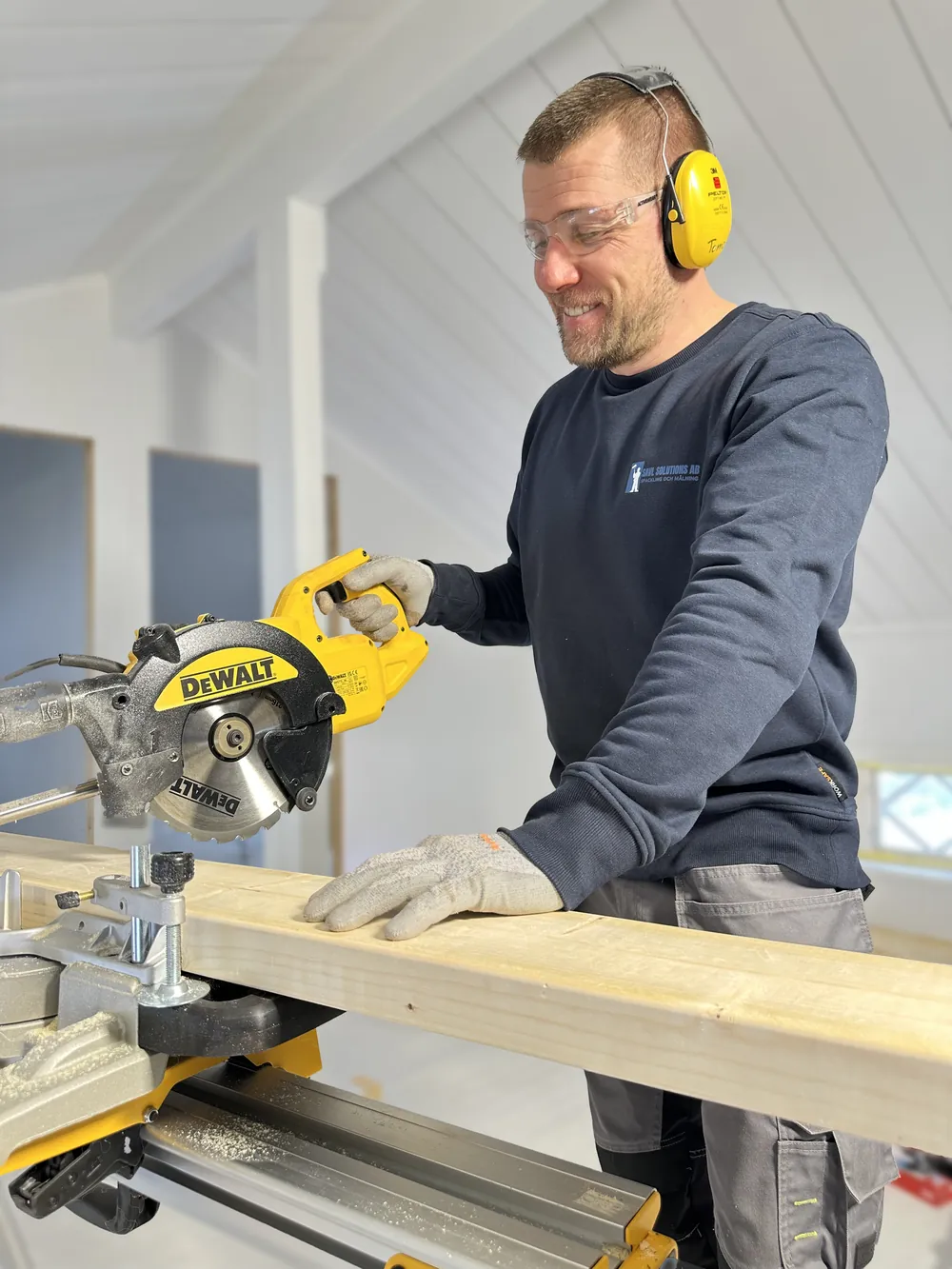 Snickare kapar reglar med gersåg för byggkonstruktion. Vi utför ombyggnation och stomresning.