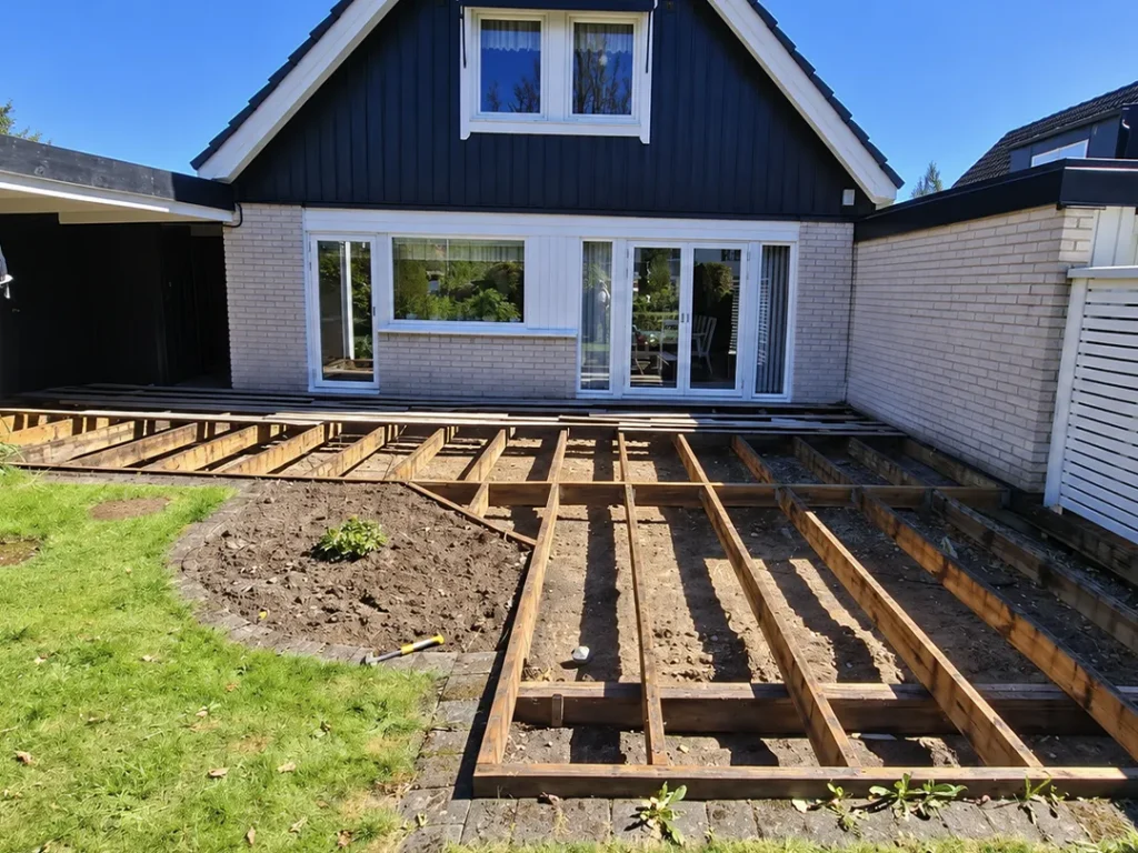 Altanrenovering i Karlstad med husfasad och pågående terrassbygge där den gamla altanen har rivits och underkonstruktionen syns.