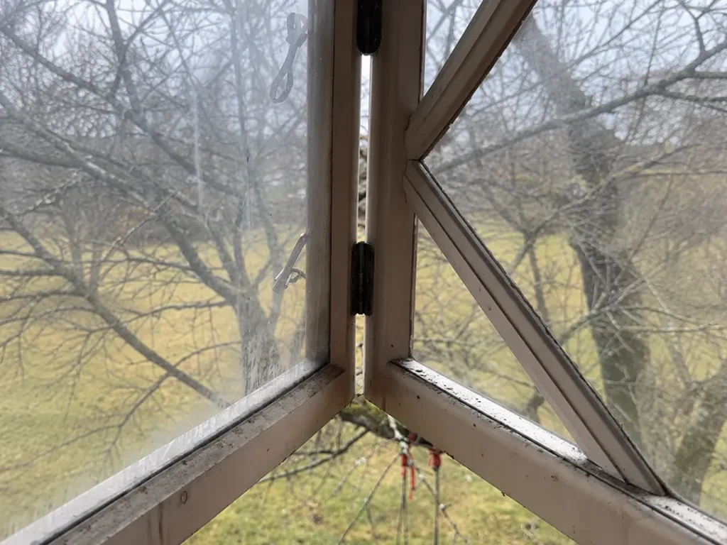 Gammalt träfönster före fönsterrenovering i Karlstad med sliten färg och smutsiga fönsterbågar.