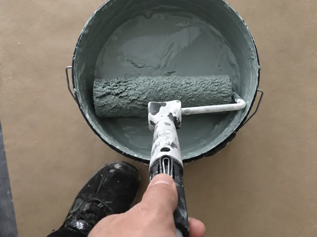 Grågrön väggfärg och roller inför invändig målning i Karlstad